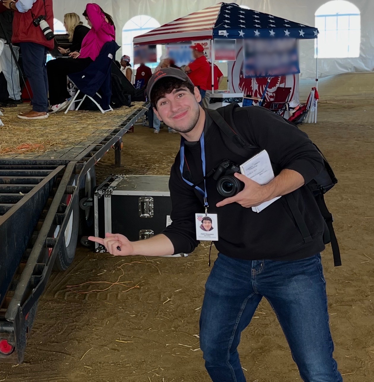 Nick holding a camera and notebook while covering a rally.